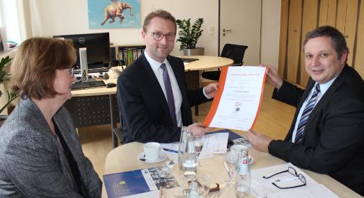 Qualität mit Gütesiegel: Nach gründlicher Überprüfung durch den TÜV-Nord konnte Erster Kreisbeigeordneter Dr. Jens Mischak (Mitte) bereits zum dritten Mal für die Vogelsberger Kreisverwaltung die Urkunde mit dem RAL-Gütesiegel entgegennehmen. Dr. Frank Wendzinski (Geschäftsführer der IHK Gießen-Friedberg) freute sich bei der Übergabe über den hohen Dienstleistungsstandard im Landratsamt. Links im Bild Betriebswirtin Andrea Ortstadt, die im Sachgebiet Wirtschaftsförderung für das Audit und die Re-Testierung verantwortlich zeichnete / Foto: Erich Ruhl-Bady