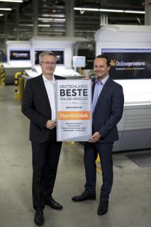 diedruckerei.de-CEO Dr. Michael Fries (l.) und CFO Dirk A. Müller halten das neue Siegel hoch: In der aktuellen Kundenumfrage von Handelsblatt und ServiceValue setzte sich diedruckerei.de gegen Mitbewerber durch und darf sich „Deutschlands bester Online-Händler“ nennen / Copyright: Onlineprinters GmbH