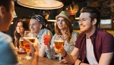 Menschen sitzen am Tisch mit Getränken in der Hand