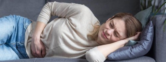 ahAGSrK9tuLqEENF_frau-mit-bauchschmerzen-auf-sofa-1-.jpg