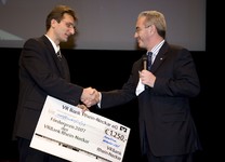 Direktor Peter Koch (rechts) von der Volksbank Rhein-Neckar übergibt an Apostolos Uzunidis (links) den Scheck als Anerkennung für seine Existenzgründung im Jahr der Meisterprüfung. 