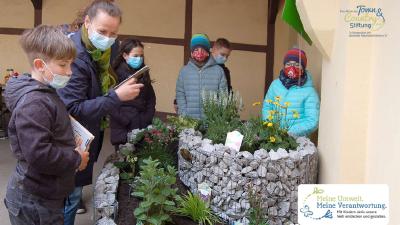Hort-Leiterin Manuela Schildhauer freut sich mit den Kindern über die NektarTankstelle und das WildbienenHaus