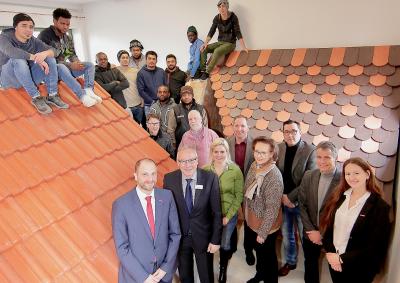 Die Teilnehmer der von der Handwerkskammer initiierten Praxislernwerkstatt in Pfarrkirchen im Landkreis Rottal-Inn präsentieren den Projektkoordinatoren ihr selbstgebautes Modellhaus. Foto: obx-news/Kökeny Studios